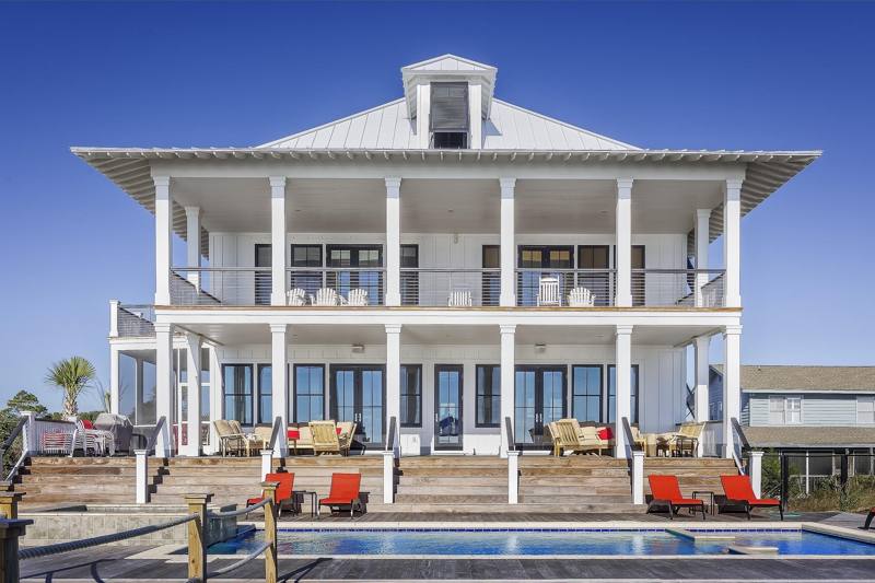 Two-story white beach house with a pool